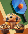 blue and black pickleball paddle with orange ball with a blueberry muffin and two chocolate muffins on a court 