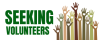Green letters spelling "Seeking volunteers" and several differend colored raised hands with with hearts on each palm